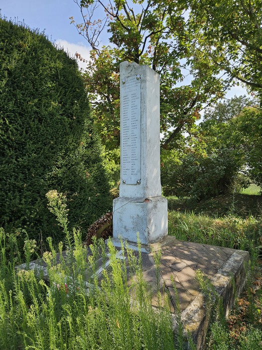 Monumento ai Martiri di Sabbiuno immerso nel verde, con una stele commemorativa visibile.