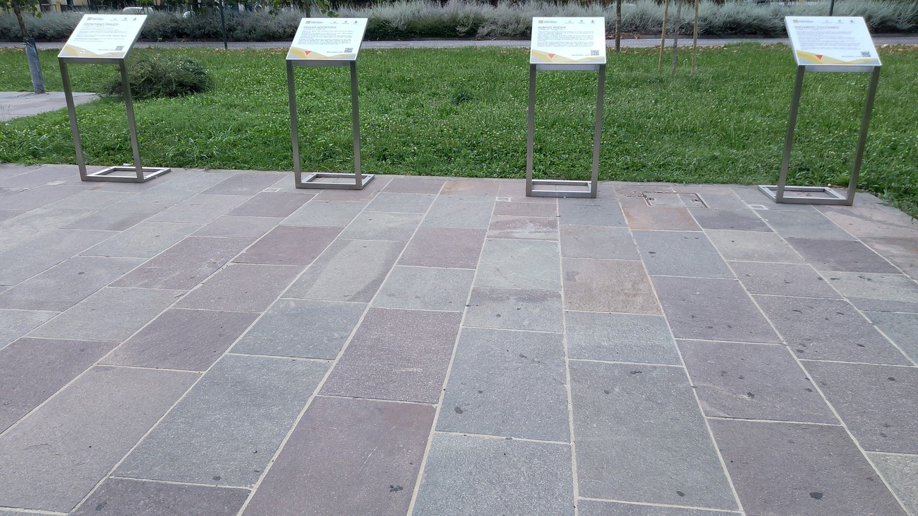 Pietre d'inciampo nel Giardino della Memoria, illuminate da un verde prato circostante.