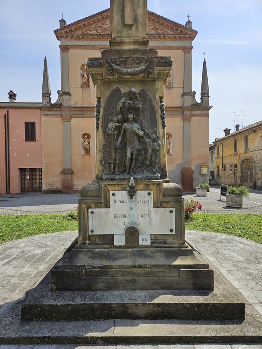 Monumento ai Caduti di Castiglione d'Adda, con statue e dettagli architettonici, immerso in un ambiente urbano.