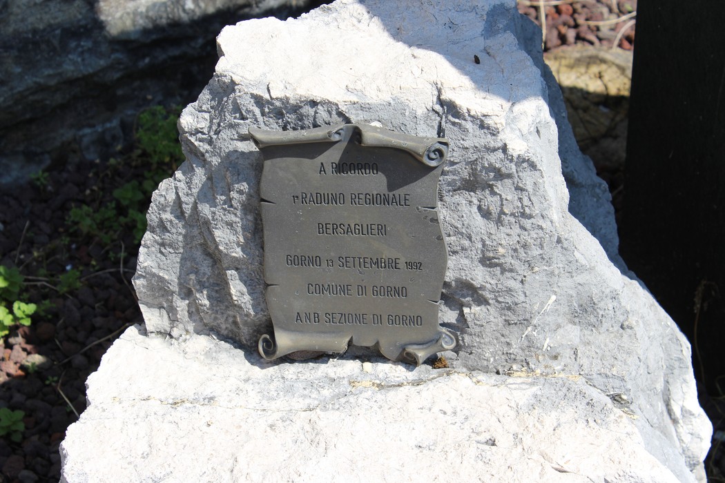 Monumento a Riccardi con targa commemorativa su una pietra, immerso in un contesto naturale.