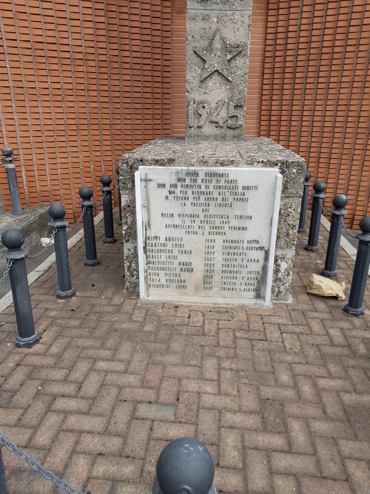 Monumento ai Martiri del Cabina con base in pietra e colonna, circondato da catene e paletti.