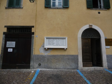 Lapide commemorativa dedicata ai partigiani caduti, posta su una parete in un contesto urbano.