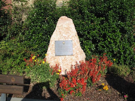Cippo commemorativo circondato da aiuole fiorite, dedicato alle vittime civili e militari.