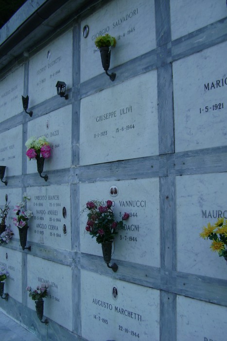 Sepolcri commemorativi dedicati ai caduti per la libertà, adornati da fiori in ricordo.