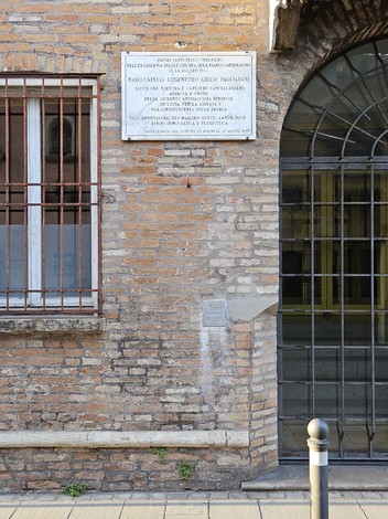 Lapide commemorativa dei Tre Martiri, situata su una parete di mattoni a vista.