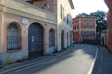 Vista di un vicolo con edifici colorati e una lapide a Pittaluga visibile sui muri. Atmosfera tranquilla e suggestiva.