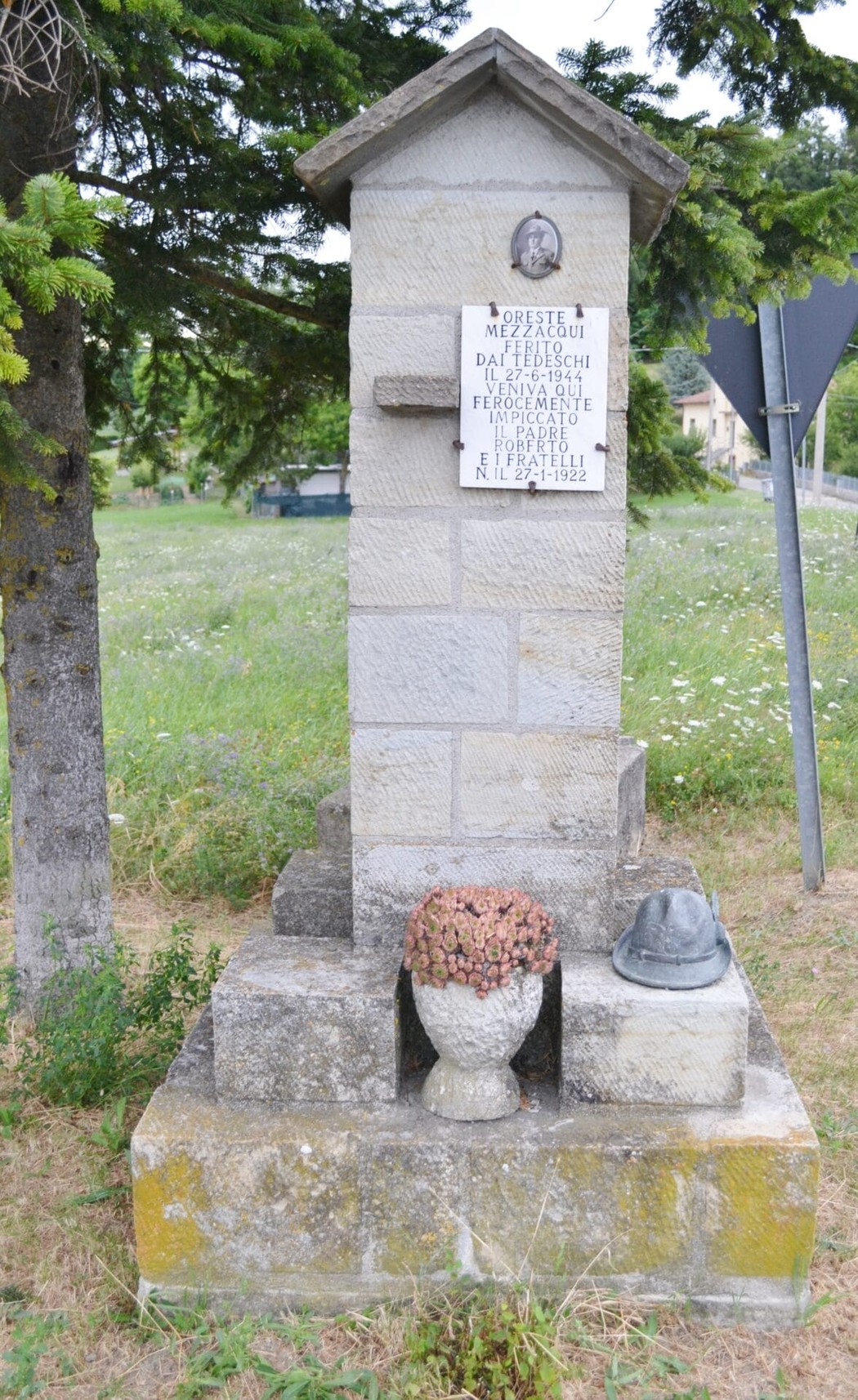 Monumento a Mezzacqui, dedicato ai caduti, con base quadrata e decorazioni floreali.