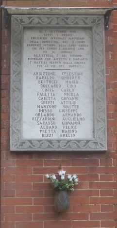 Lapide commemorativa ai caduti di Belvedere, con i nomi dei caduti incisi nel marmo e un vaso di fiori decorativo.