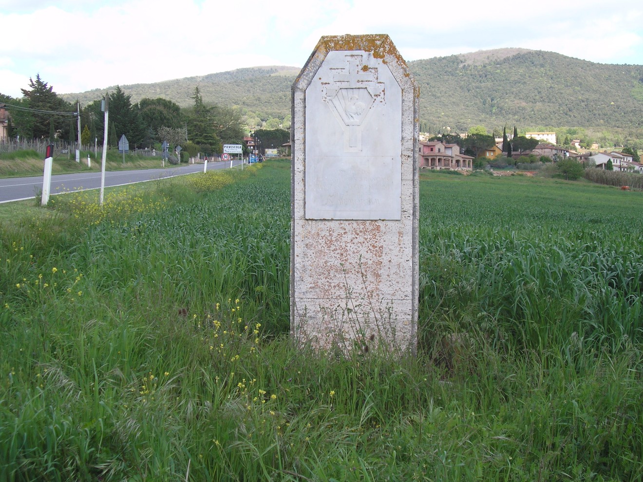 Cippo commemorativo dedicato ai caduti francesi, situato in un campo, circondato da natura.