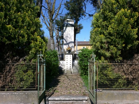 Monumento ai Caduti di Budrio, circondato da verde, commemorativo e sobrio nella sua architettura.
