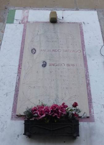 Lapide commemorativa dedicata a Angelino Barzago e Angelo Beretta, con fiori decorativi.