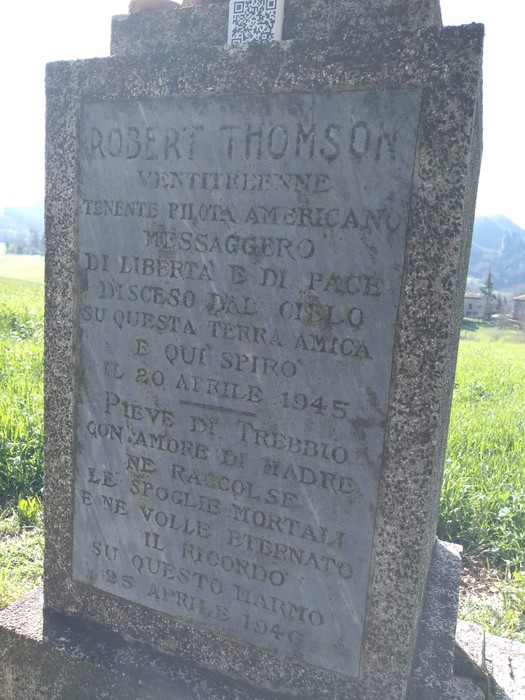 Cippo commemorativo dedicato a Robert Thomson, pilota americano, in un contesto naturale sereno.
