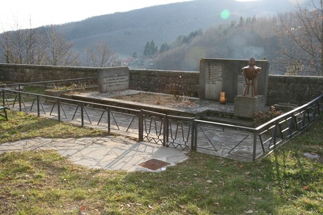 Monumento ai caduti con targa commemorativa, immerso nella natura e circondato da monti.