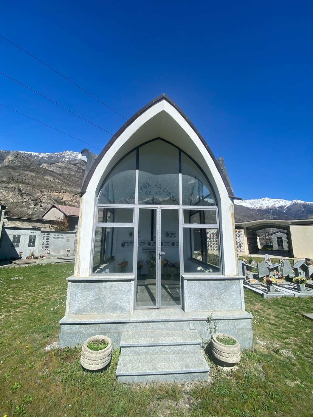 Cappella dei caduti per la libertà, con architettura moderna immersa in un paesaggio montano.