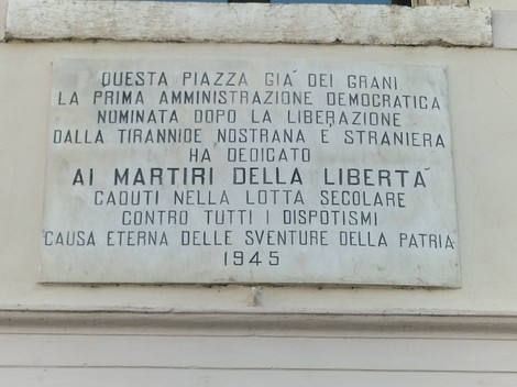 Lapide commemorativa dedicata ai Martiri della Libertà, situata in una piazza storica.