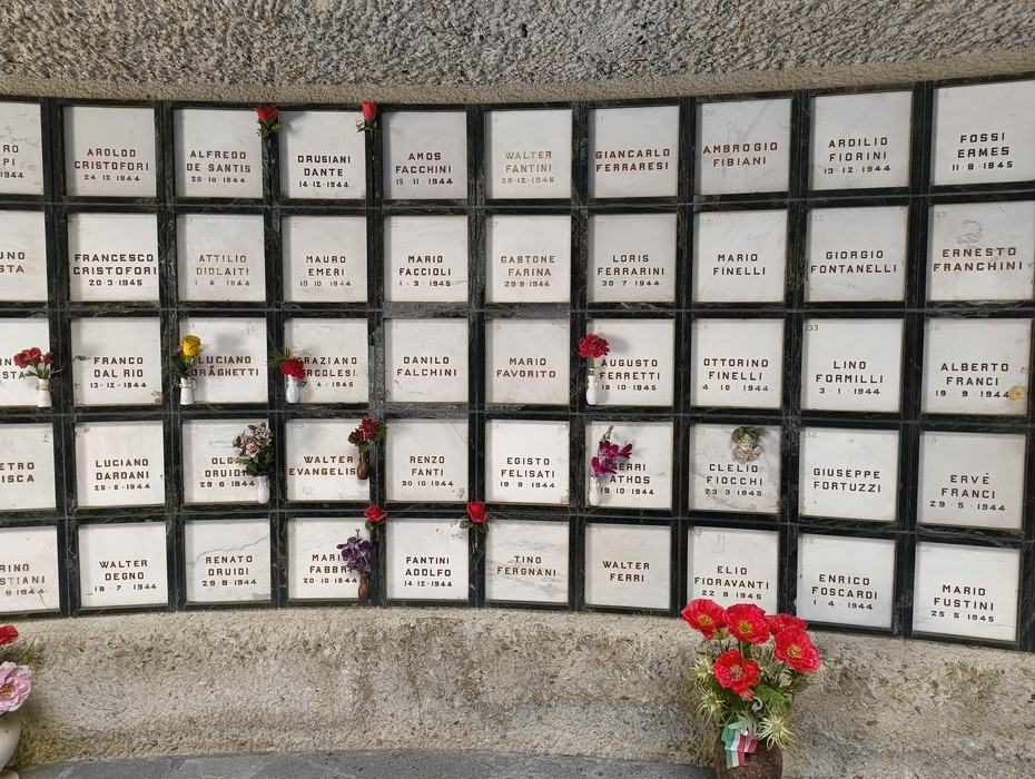 Monumento Ossario dedicato ai caduti partigiani, con placche commemorative e fiori.
