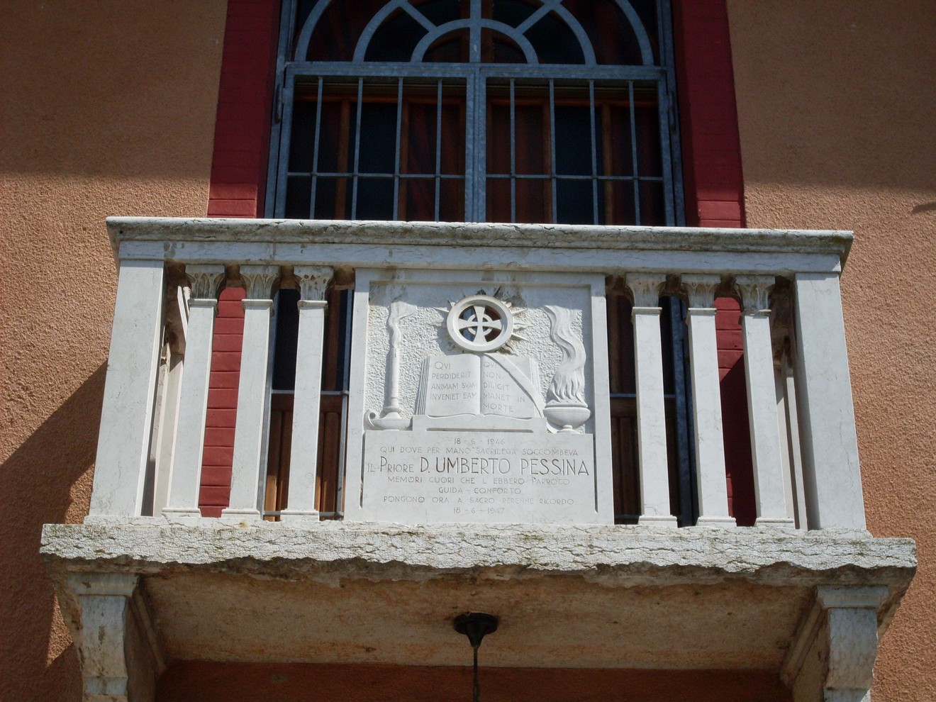 Lapide commemorativa dedicata a Pessina, situata su un balcone in una facciata storica.
