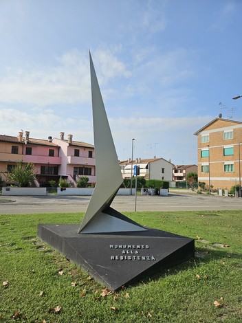 Monumento alla Resistenza: scultura moderna con forma slanciata, inserita in un contesto urbano e verde circostante.