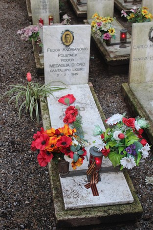 Tombe decorate con fiori e lumini, dedicate ai caduti per la Libertà in un cimitero. Atmosfera di rispetto e commemorazione.