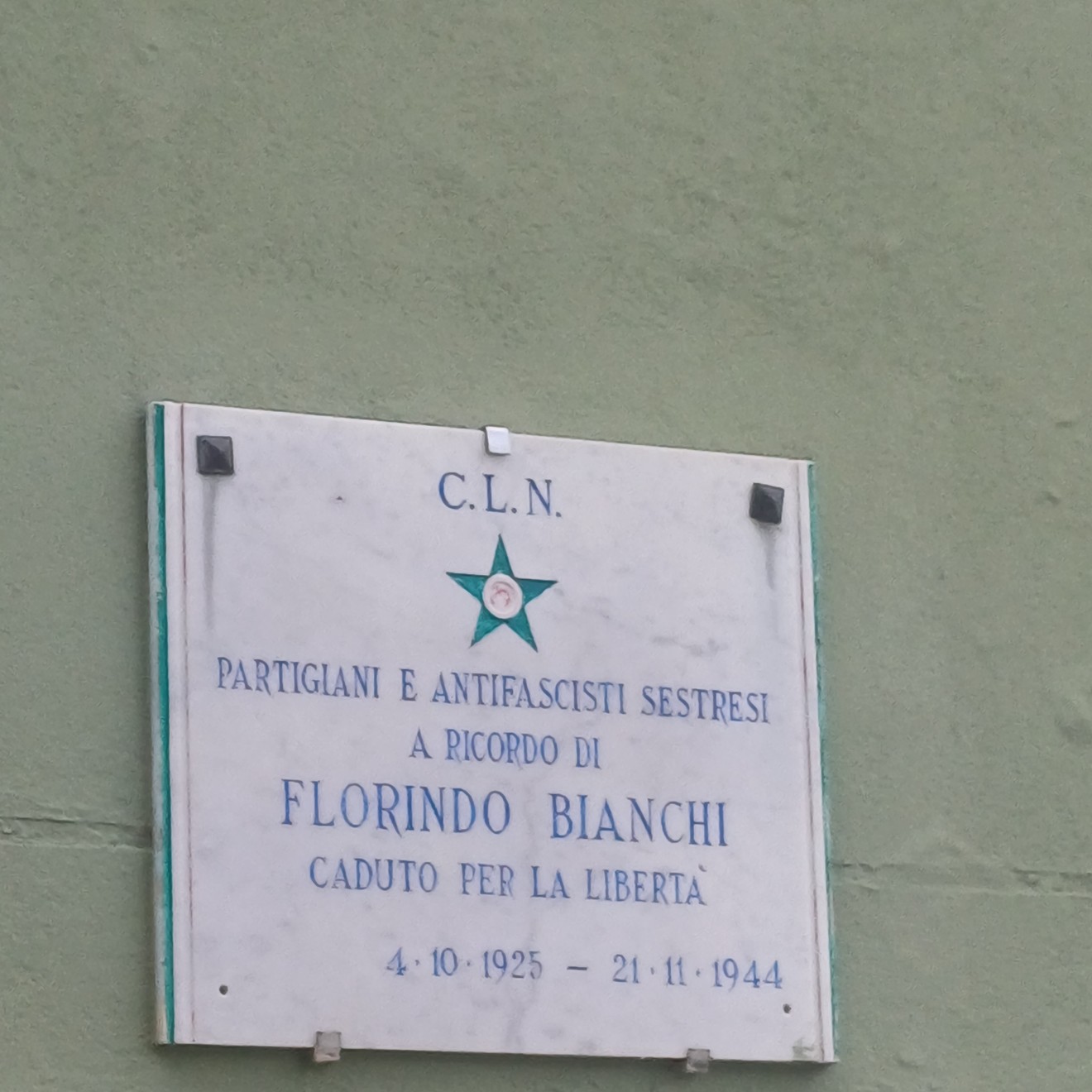 Lapide marmorea con stella verde del C.L.N. e iscrizione, fissata su parete esterna.
