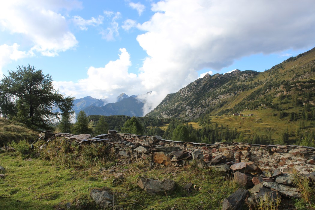 Panorama del Vecchio rifugio dei Laghi Gemelli immerso nella natura montana con vette e nuvole.