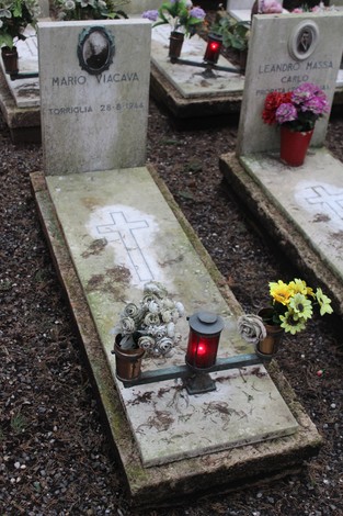 Tombe perpetue dei caduti per la Libertà, con lumini e fiori, in un ambiente di rispetto e memoria.