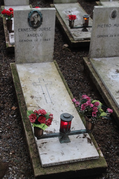 Tombe con fiori e lumini, in memoria dei caduti per la Libertà, immerse in un'atmosfera di rispetto e commemorazione.