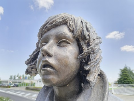 Monumento dedicato alle vittime dell'eccidio di Pratomaggiore, con un volto espressivo in bronzo.