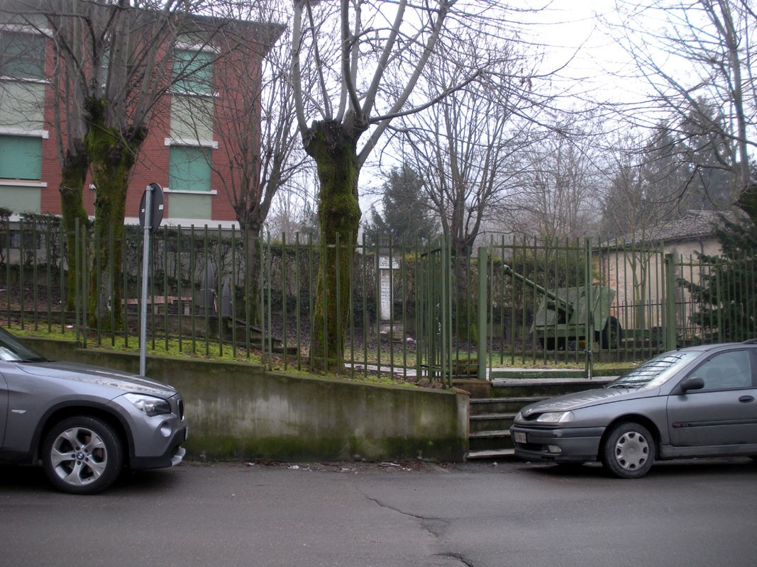 Monumento ai caduti civili di Santa Giulietta, con alberi e recinto, in un contesto urbano.