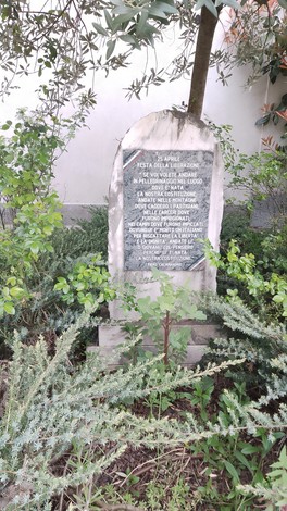 Cippo alla Liberazione immerso in un verdeggiante contesto naturale, circondato da piante e arbusti.