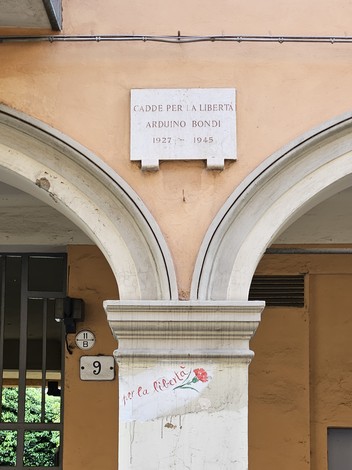 Lapide commemorativa di Arduino Bondi, situata sotto un'arcata, con un’iscrizione storica.