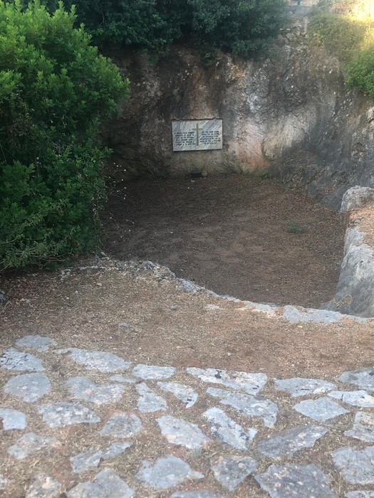 Lapide commemorativa in un'area scavate, circondata da vegetazione e pietre, ricorda gli ufficiali caduti.