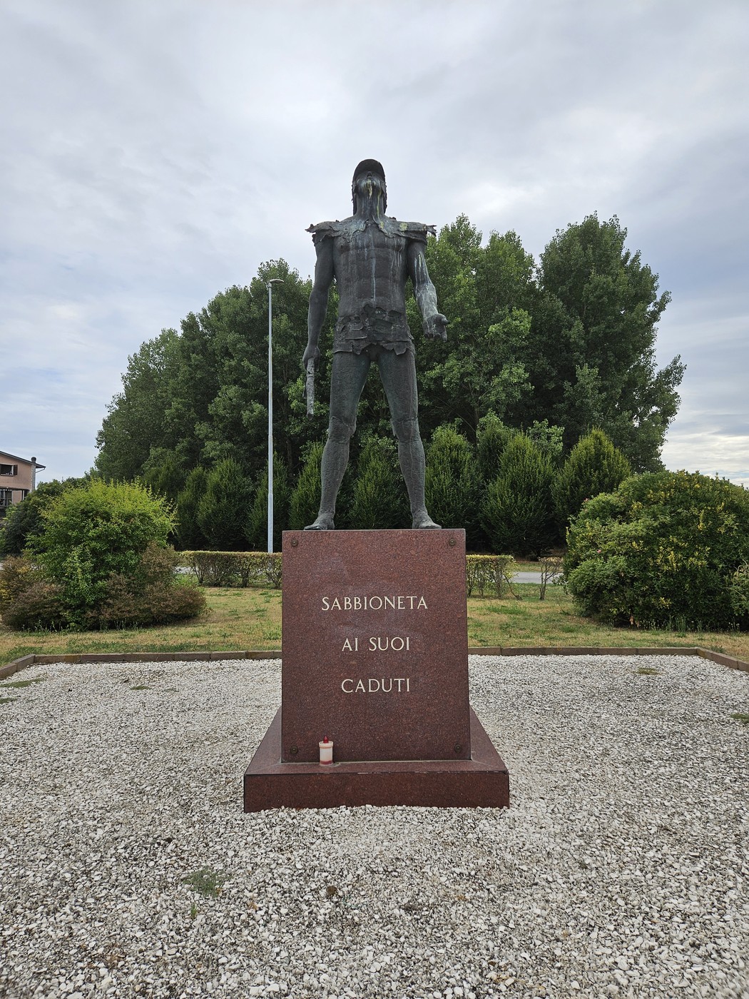 Monumento commemorativo ai caduti di Sabbioneta, con figura imponente e base in marmo. Giardini curati circostanti.