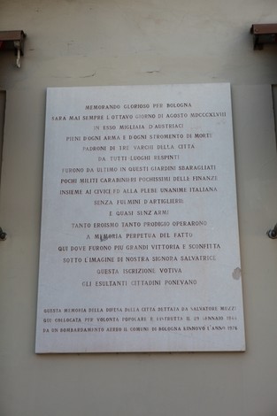 Lapide commemorativa che ricorda la difesa di Bologna, con iscrizioni storiche e significati patriottici.