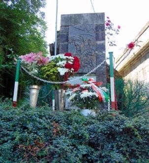 Monumento dedicato ai Martiri del Ponte della Pietà, adornato con fiori e omaggi commemorativi.
