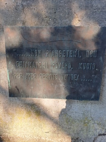 Monumento ai Caduti con incisione commemorativa su una parete in bronzo, circondata da un'atmosfera solenne.