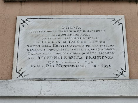 Lapide commemorativa per il decennale della Resistenza, celebrando i sacrifici e la libertà.