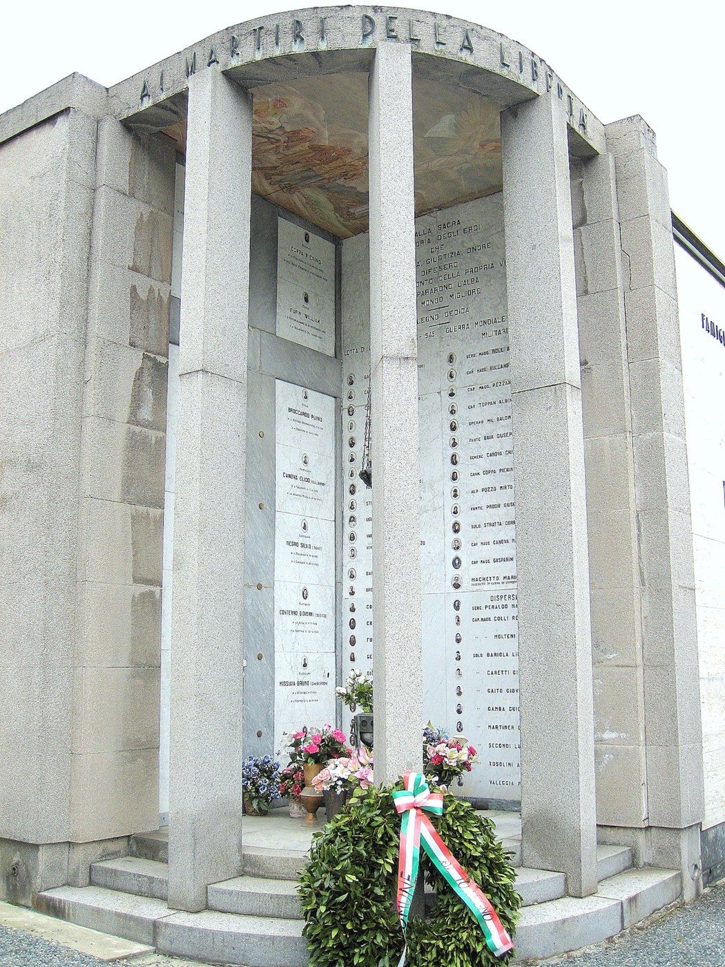 Sacrario ai martiri della Libertà, monumento in pietra con nomi e omaggi floreali in ricordo dei caduti.