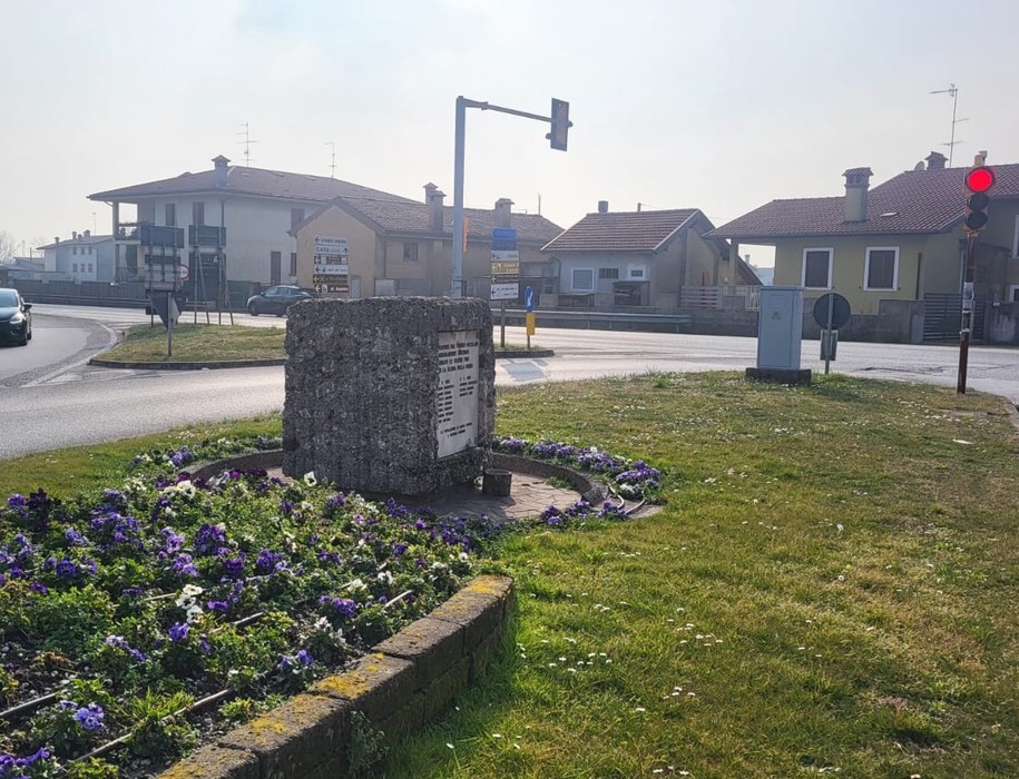 Monumento ai Martiri di Taboga in una rotonda, circondato da fiori e strade, con edifici sullo sfondo.