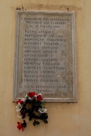 Lapide commemorativa in onore dei martiri di Ca' Giustinian, decorata con fiori, a ricordo delle vittime del fascismo.
