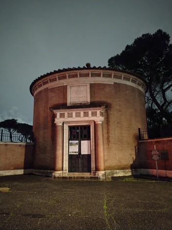 Cimitero di guerra del Commonwealth con struttura monumentale in un'atmosfera notturna e elementi architettonici classici.