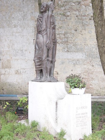 Monumento in bronzo dedicato a Morgantini e Baldetti, con decorazioni floreali, situato in un contesto storico.