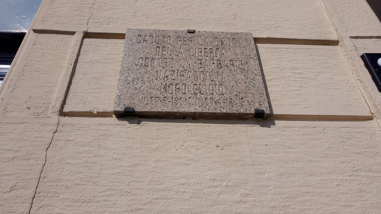 Lapide commemorativa in pietra dedicata a un evento storico, affissa su una parete.