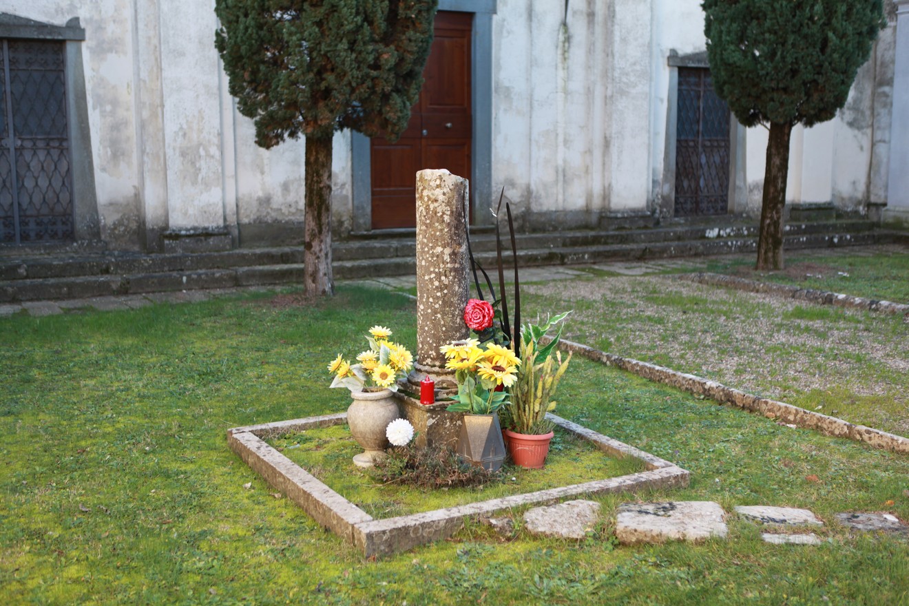 Cippo commemorativo con fiori, dedicato ai caduti per la libertà, situato in un contesto tranquillo.