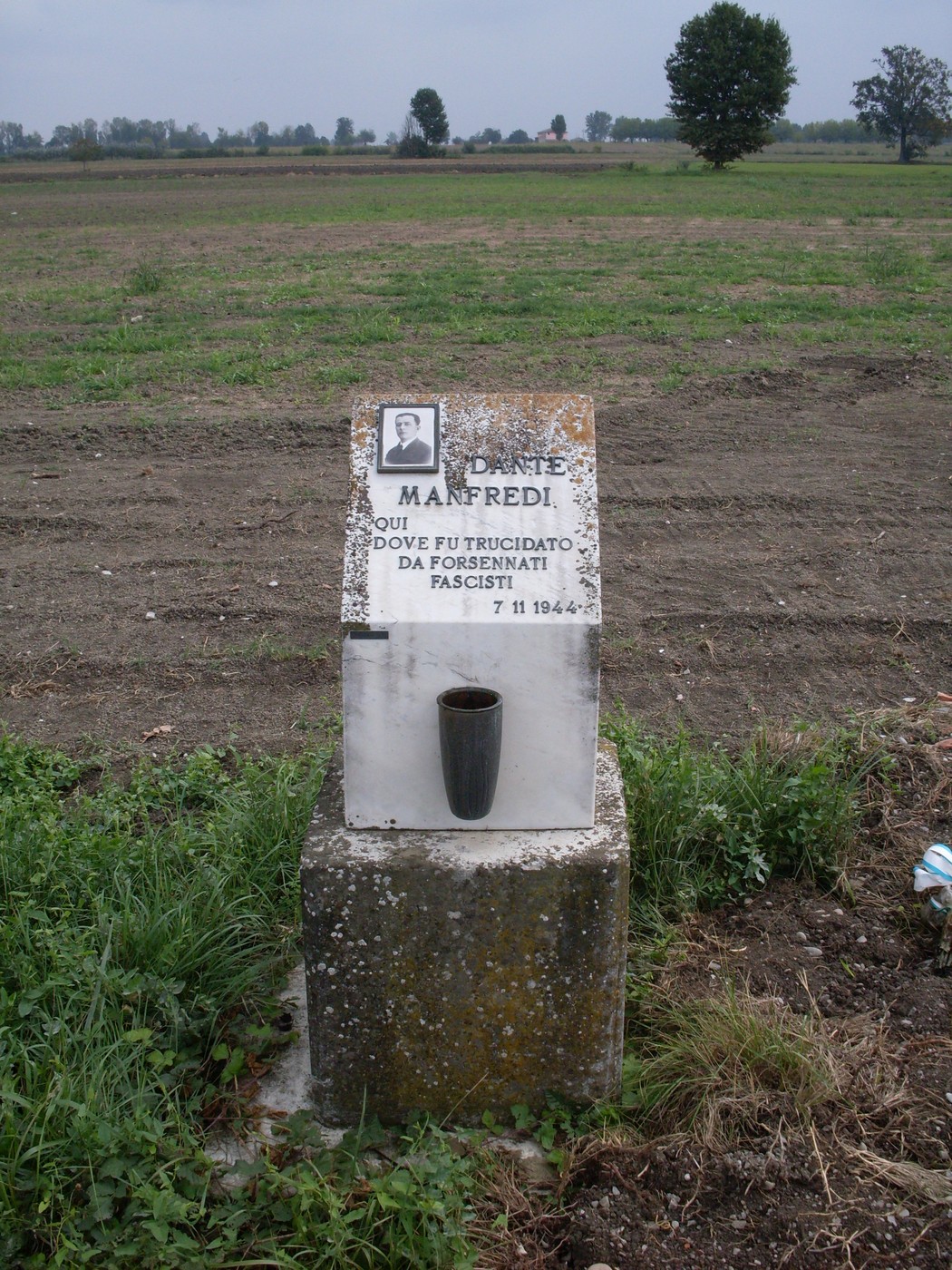 Cippo commemorativo di Manfredi, vittima di un'eccidio fascista, situato in un campo aperto.