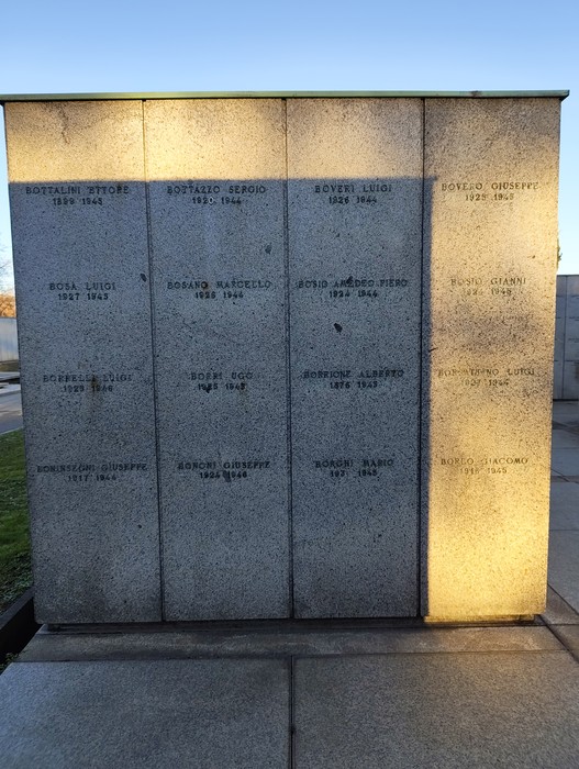 Monumento commemorativo con nomi incisi su una parete di pietra al Campo della Gloria.