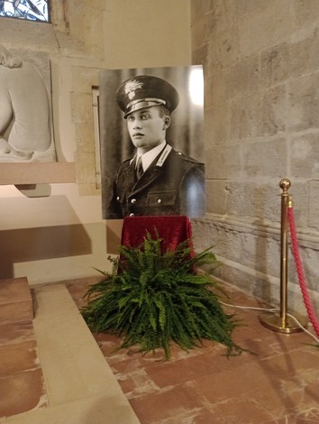 Il sepolcro di D'Acquisto, con un ritratto di lui in uniforme e decorazioni floreali.