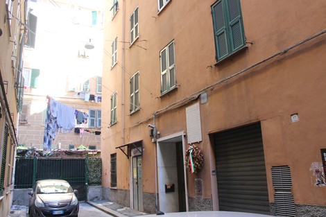 Vista di un vicolo con case colorate e abiti stesi, evidenziando l'atmosfera urbanistica di Buranello.