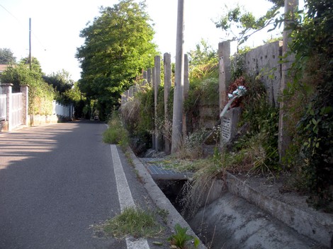 Lapide commemorativa ai fratelli Zoncada lungo una strada, circondata da vegetazione e un ambiente rurale.