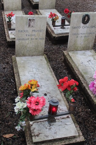 Tombe monumentali dedicate ai caduti per la libertà, adornate da fiori e candele in un cimitero.